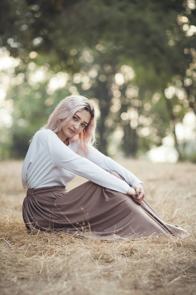 jong mooi vrouw in een lange jurk op een achtergrond van droog gras zitten op glade in het bos, romantisch meisje ontspannen alleen in de natuur, natuurlijke vrouwelijke portret - Foto, afbeelding