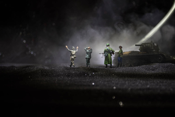 Kampfszene. militärische Silhouetten Kampfszene auf Krieg Nebel Himmel Hintergrund. ein deutscher Soldat erhob die Waffen, um sich zu ergeben. Spielzeugsoldaten aus Plastik mit Gewehren, die den feindlichen Soldaten gefangen nehmen. - Foto, Bild