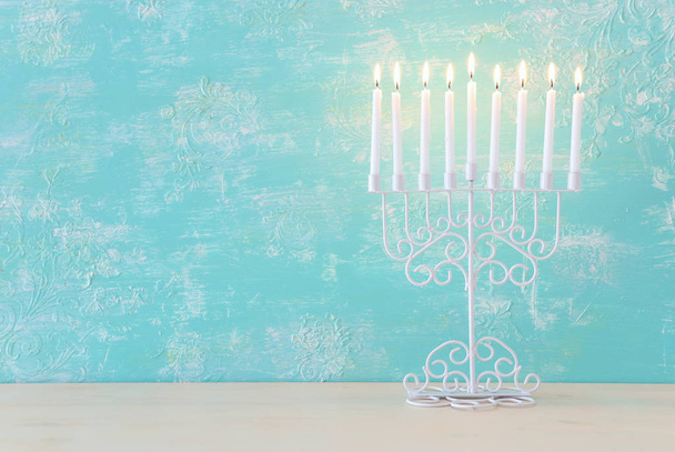 Religion image of jewish holiday Hanukkah background with menorah (traditional candelabra) and candles over pastel blue background - Foto, Bild