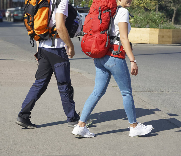 GDANSK, POLAND - AUGUST 27, 2019: Young travelers walking in the european city. Man and woman having vacation. Backpackers, traveling and tourism. Two backpackers wearing summer cloths walking in street. - Foto, afbeelding