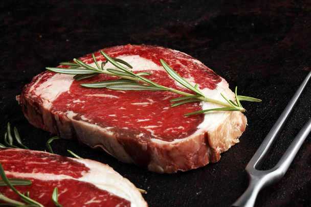rohes frisches Fleisch Ribeye Steak, Würze und Fleischgabel auf rustikalem B - Foto, Bild