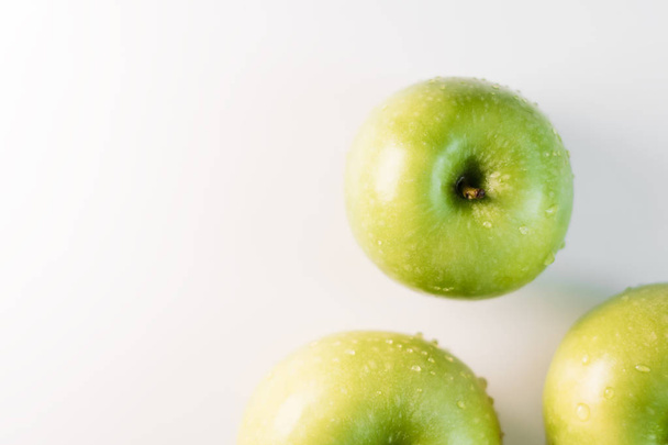 Fresh green apples with water droplets on a white glossy kitchen table. Tasty bright juicy fruits. Healthy eating. Isolated object. - Photo, image