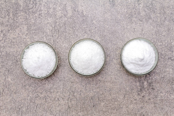 Trois types de sel de mer : grand, moyen et petit. Vue de dessus, gros plan, sur un fond de pierre grise
. - Photo, image