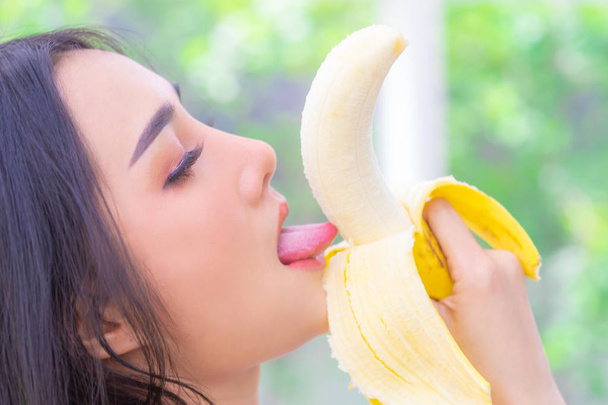 Asian woman is licking yellow Banana for good test and senuality - Fotografie, Obrázek