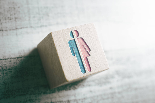Geschlechtszeichen für Mann und Frau halbiert auf einem Holzblock auf einem Tisch - Foto, Bild