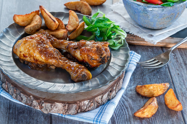 Chicken drumsticks in ginger beer sauce with potato wedges and salad on a plate - Photo, Image