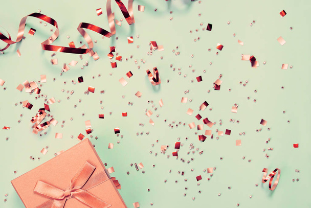 Caja de regalo sobre fondo de menta con confeti brillante. Vacaciones y
  - Foto, imagen