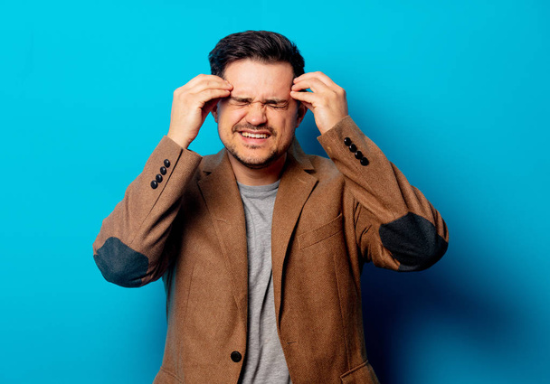 Mann mit Kopfschmerzen auf blauem Hintergrund  - Foto, Bild