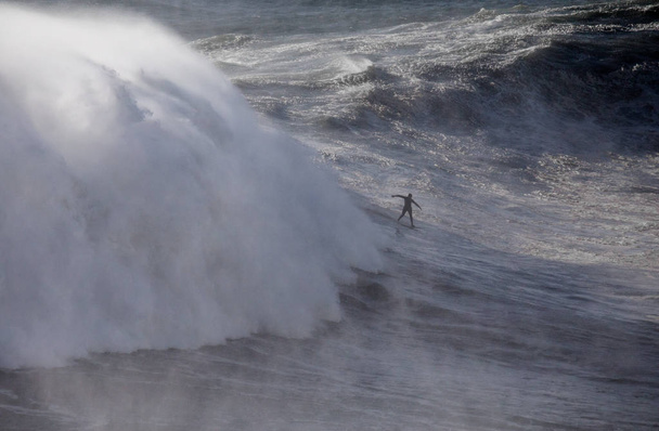 ポルトガルのナザレ島ノースビーチで大きな波をサーフィン. - 写真・画像