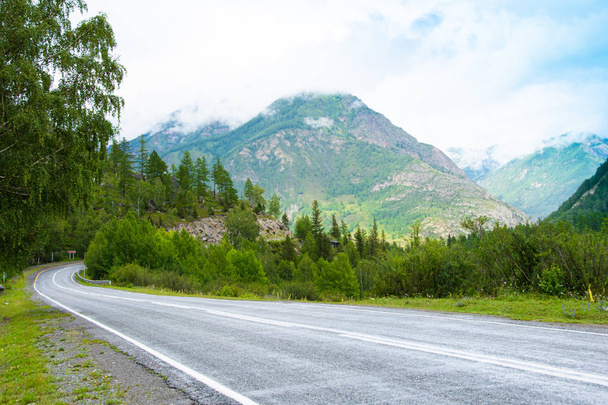 Asphalt road in mountain valley with ridge of rocks on horizon. Comfortable travel by car in wild - Φωτογραφία, εικόνα