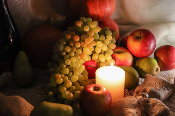 Herbsternte. weiße Trauben von Sultaninen, Äpfeln, Birnen und Kürbissen mit sanftem Kerzenlicht Stillleben auf Sacktuch - Foto, Bild