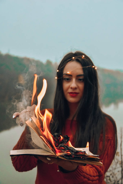дівчина тримає палаючу книгу полум'я вогню магія
  - Фото, зображення
