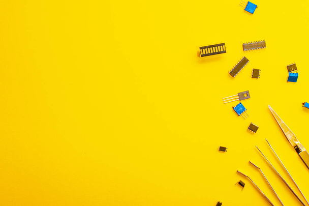 Tweezers and electronic parts on a yellow background - Fotoğraf, Görsel