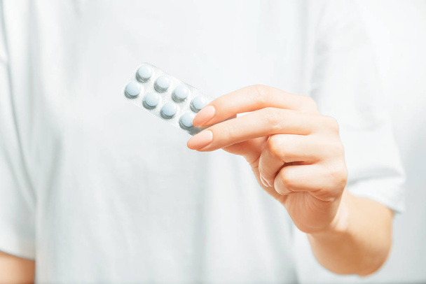 Vrouwelijke hand die een blister met medische tabletten vasthoudt. - Foto, afbeelding