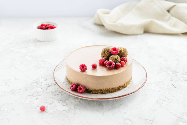 Raw cocoa cake garnished with energy balls and raspberries. Gluten free. - Photo, Image