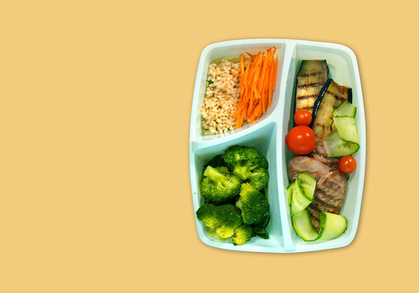  Lunchdoos met broccoli, vlees, aubergine, wortel, rijst, tomaat, komkommer. Kopieerruimte. - Foto, afbeelding