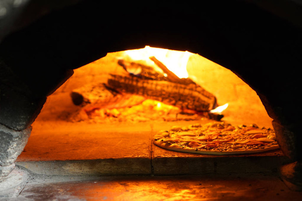 Making authentic Italian pizza in the stone oven stove - Zdjęcie, obraz