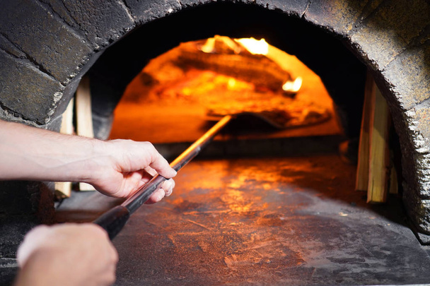 Pizza maker hands close-up. Pizzeria stone stove. - Foto, afbeelding