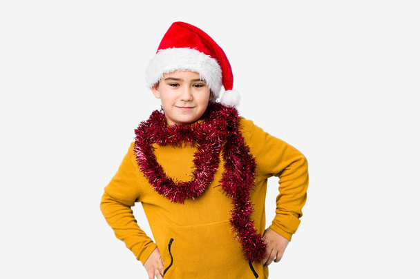 Little boy celebrating christmas day wearing a santa hat isolated confident keeping hands on hips. - Foto, Bild