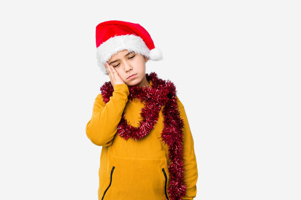 Little boy celebrating christmas day wearing a santa hat isolated who is bored, fatigued and need a relax day. - Фото, изображение