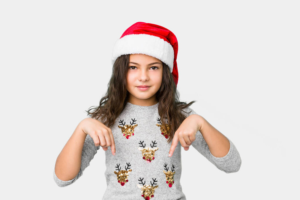 Menina celebrando o dia de Natal aponta para baixo com os dedos, sentimento positivo
. - Foto, Imagem