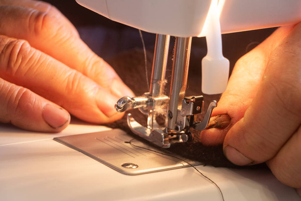 Hombre reparando una ropa con una máquina de coser
 - Foto, Imagen