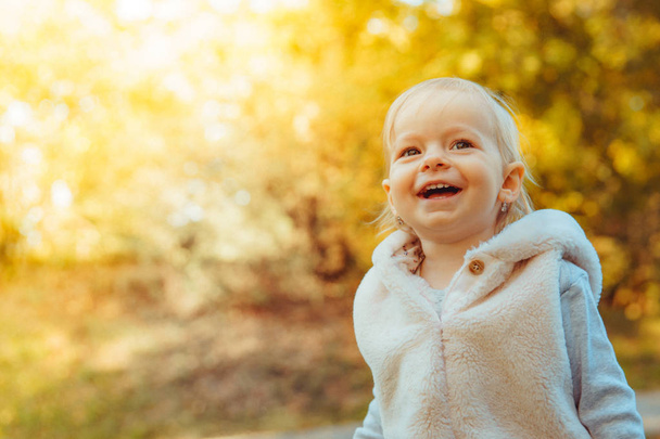 Onnellinen vauva iloitsee syksyllä sää ja leikkii niityllä puistossa
 - Valokuva, kuva