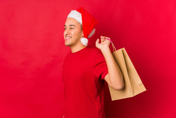 Junger Mann hält ein Geschenk an Weihnachten in der Hand - Foto, Bild