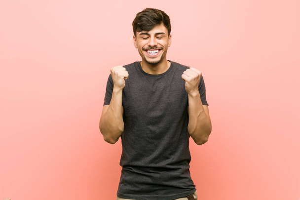 Young hispanic casual man raising fist, feeling happy and successful. Victory concept. - Photo, Image