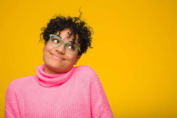 Young african american woman wearing a pink sweater dreaming of achieving goals and purposes - Photo, image