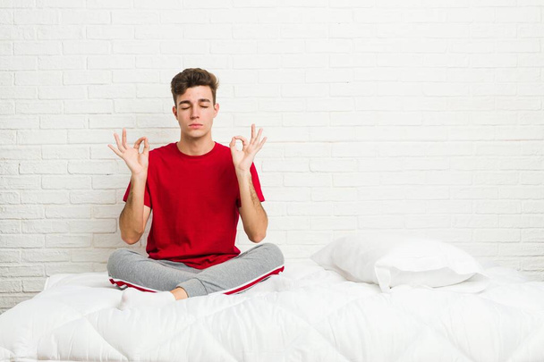 Joven adolescente estudiante hombre en la cama se relaja después de un duro día de trabajo, ella está realizando yoga
. - Foto, imagen