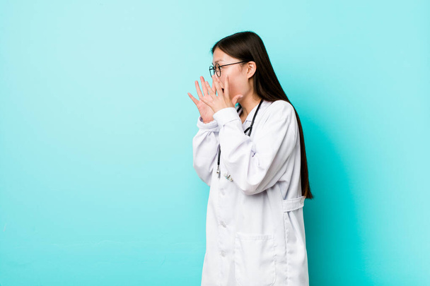 Jovem chinesa médico mulher grita alto, mantém os olhos abertos e as mãos tensas
. - Foto, Imagem