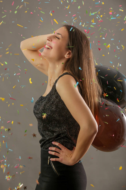 Belle femme tenant des ballons noirs et dansant sous le concept des confettis, fêtes et fêtes de fin d'année
 - Photo, image