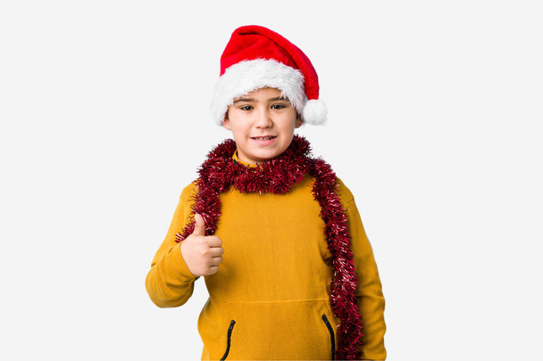 Menino comemorando o dia de Natal usando um chapéu de Papai Noel isolado sorrindo e levantando o polegar
 - Foto, Imagem
