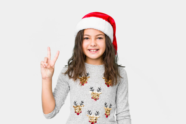 Kleines Mädchen feiert Weihnachten mit Siegeszeichen und breitem Lächeln. - Foto, Bild