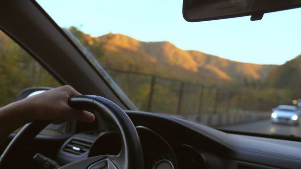 За рулём человека стоит руль, за окном великолепный осенний горный пейзаж и разноцветные осенние деревья. поездка на машине
 - Фото, изображение