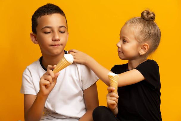 Happy Siblings eating ice-cream on color background - Fotó, kép