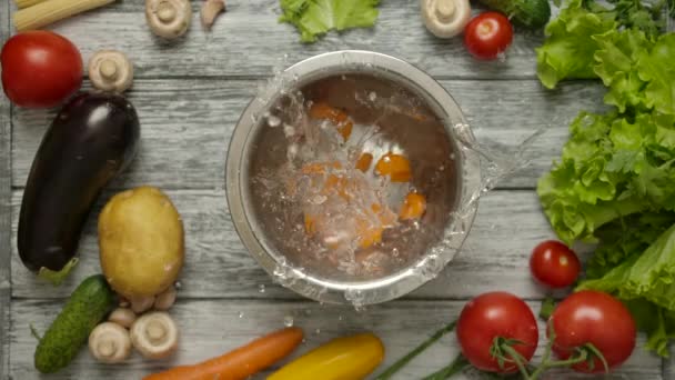 Rodajas de zanahoria cayendo en un recipiente de metal con agua - Imágenes, Vídeo