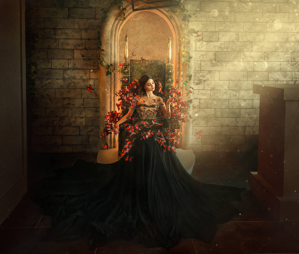 gothic dark queen sits in castle on golden throne. black dress with butterflies. Brick wall, large gothic room, magical sun rays from window. Long train fashionable silk skirt. Glamorous fantasy woman - Foto, Imagem