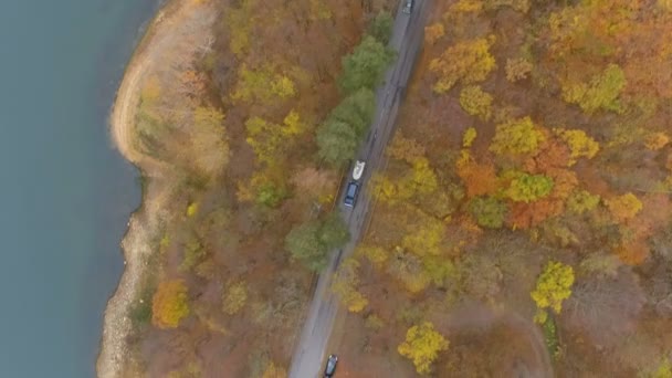 Drone chasing suv or car twoing a white boat, driving along asphalt road near clear lake - Video