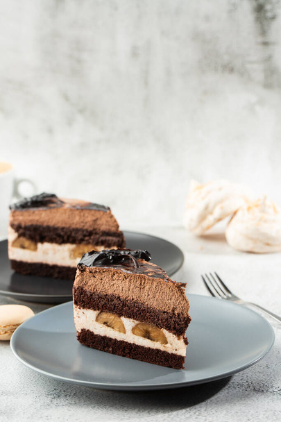 Banana chocolate cake on gray plate on marble background. Selective focus. Vertical photo. Menu for bakery. cafe menu. Pastry. Delicious and sweet dessert at cafe restaurant. - Photo, image