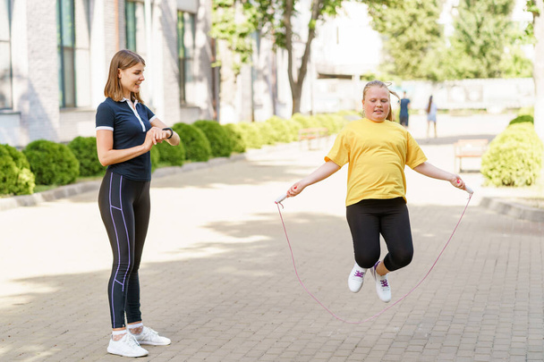 Girl jumping with a rope, doing cardio workout under her fitness trainers control - Fotografie, Obrázek
