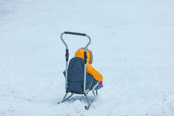 klein kind op slee glijden door de winter heuvel - Foto, afbeelding