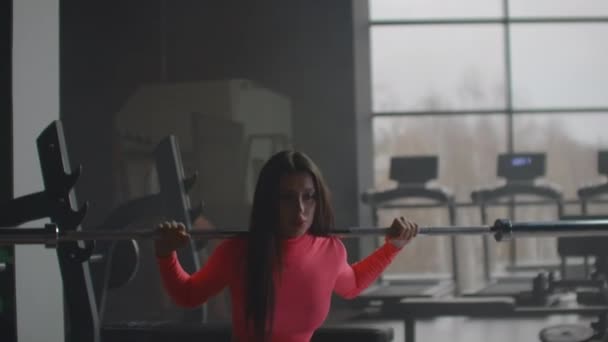 Girl crouches with barbell in gym - Footage, Video