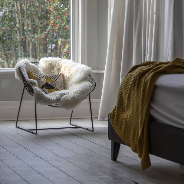 Modern armchair covered in soft furnishings in a bright bedroom - Foto, immagini