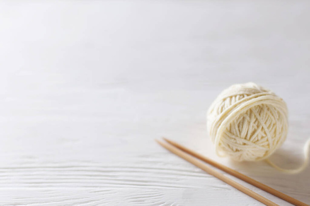 Knitting needles, white yarn, wooden background. - Fotografie, Obrázek