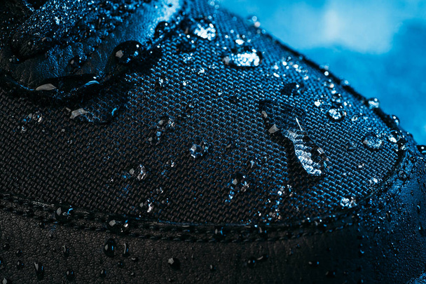 Σταγόνες νερού σε αδιάβροχο ύφασμα μεμβράνης της επιφάνειας των παπουτσιών, μακρό πλάνο. Νέα τεχνολογία στεγάνωσης για φθορά και υπόδηση για ενεργό τρόπο ζωής - Φωτογραφία, εικόνα