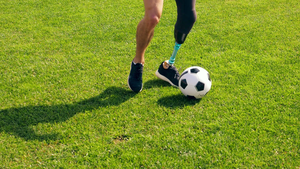 Człowiek z bioniczną nogą dryfuje piłką na zielonym trawniku. - Materiał filmowy, wideo
