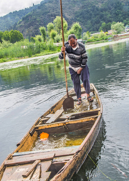 Un vecchio che toglie l'acqua che è salito sulla barca rotta
 - Foto, immagini