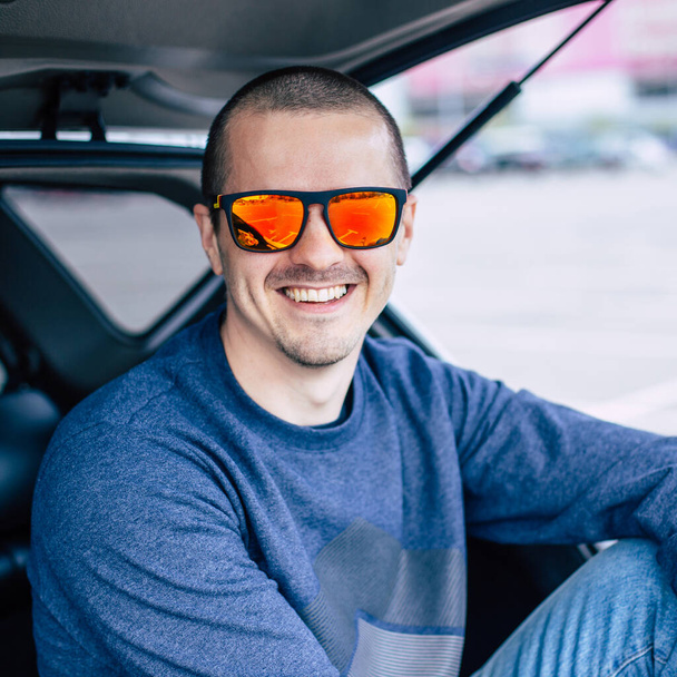 Άνθρωπος με πορτοκαλί γυαλιά ηλίου χαμογελώντας και κοιτάζοντας στην κάμερα - Φωτογραφία, εικόνα